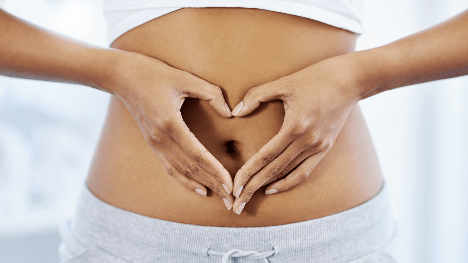 Woman gently holding her abdomen, representing leaky gut recovery and probiotic gut barrier support