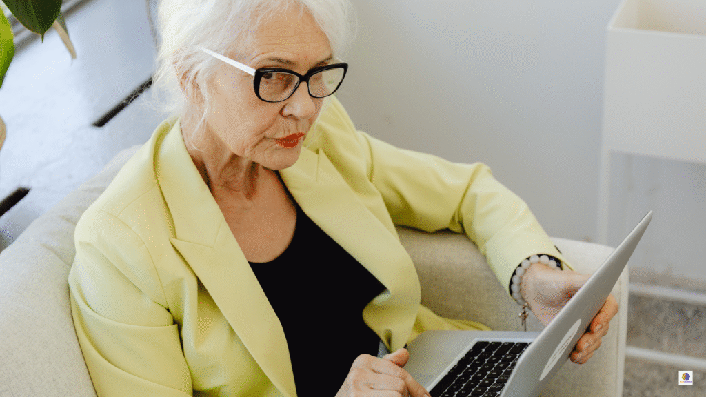 Older woman with glasses focusing on her laptop at home, illustrating attention longevity and protecting focus as you age