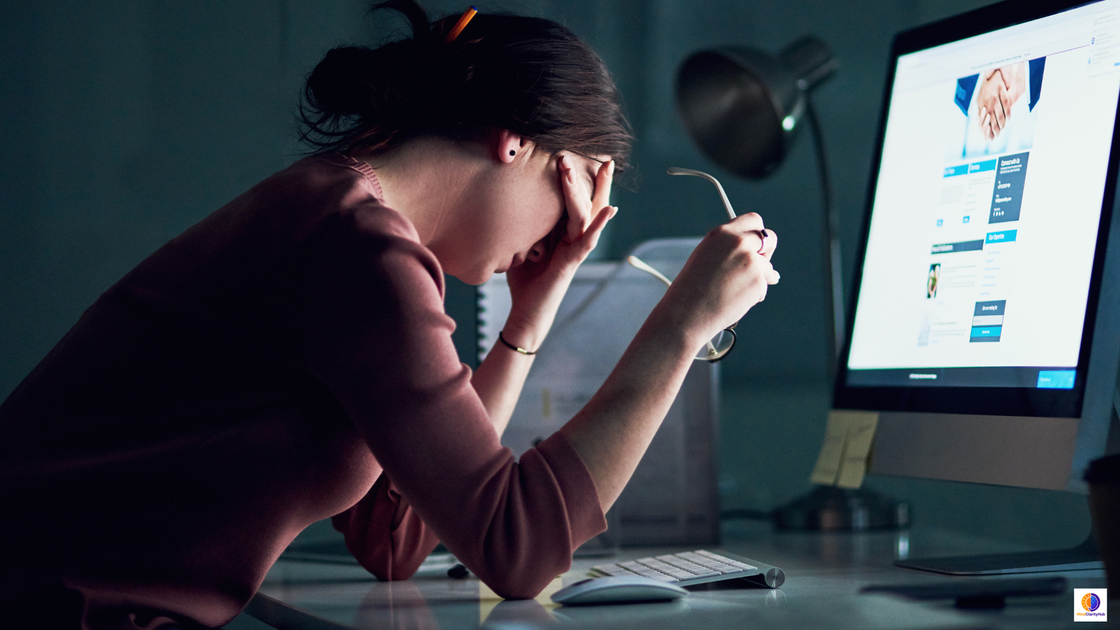 Woman at her computer, glasses off and rubbing her eyes, feeling mentally exhausted after doing nothing.