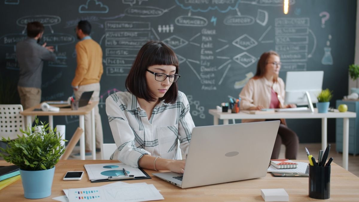 People working at desks beside a chalkboard of planning notes