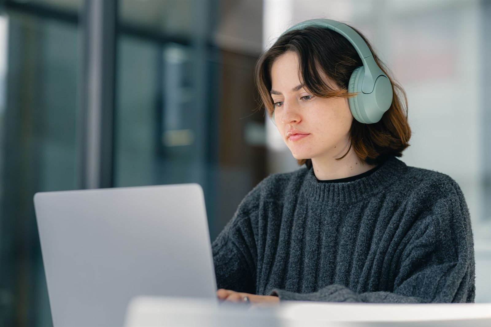 A person wearing over-ear headphones working at a laptop in an office